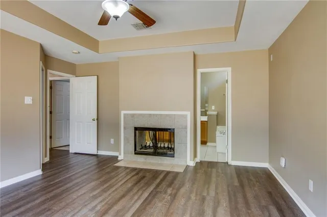 an empty room with wooden floor fireplace and windows