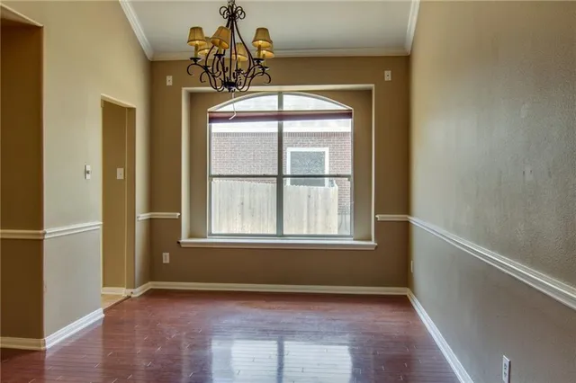an empty room with wooden floor cabinet and windows