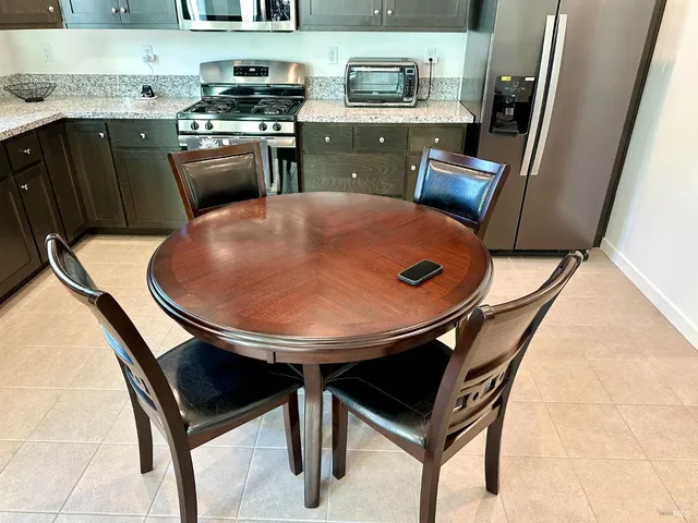 a kitchen with stainless steel appliances granite countertop a stove a sink a microwave a dining table and chairs