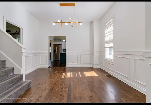 a view of an empty room with wooden floor and staircase