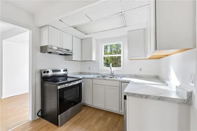 a kitchen with stainless steel appliances granite countertop a sink stove a sink dishwasher and cabinets with wooden floor