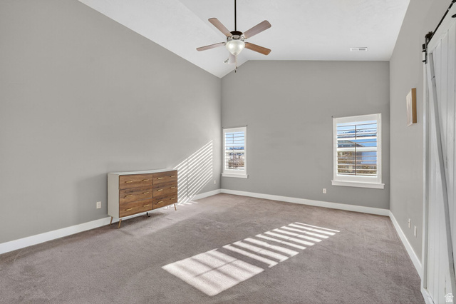 14714 South Bright Wood Road Herriman, UT 84096 - Photo 18 of 41 Unfurnished Primary Bedroom room with a barn door, high vaulted ceiling, carpet flooring, and a ceiling fan