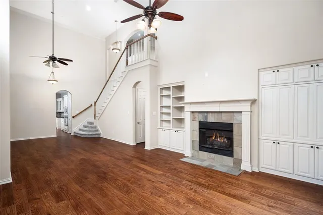 a view of an empty room with wooden floor fireplace and a window