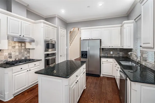 a kitchen with granite countertop a sink stove and refrigerator