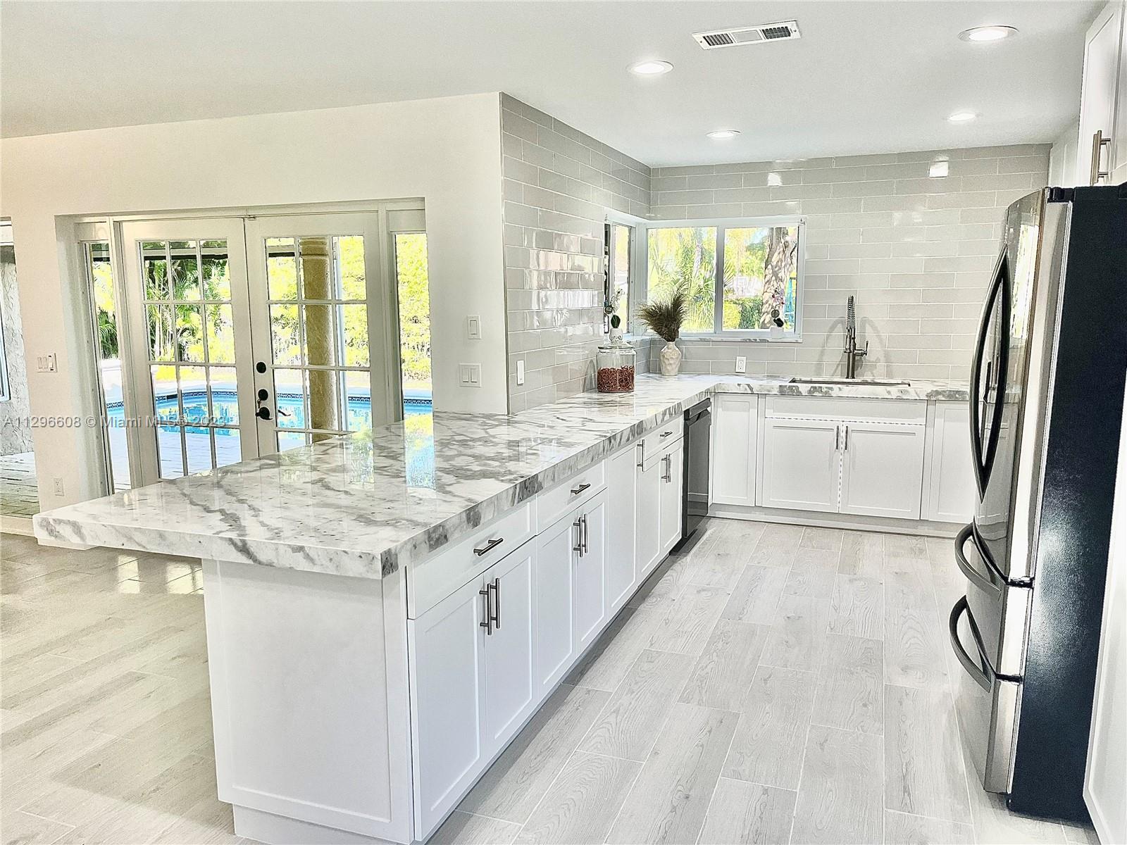 2875 Northwest 28th Street Boca Raton, FL 33434 - Photo 6 of 32 a large white kitchen with kitchen island granite countertop a large counter top and stainless steel appliances