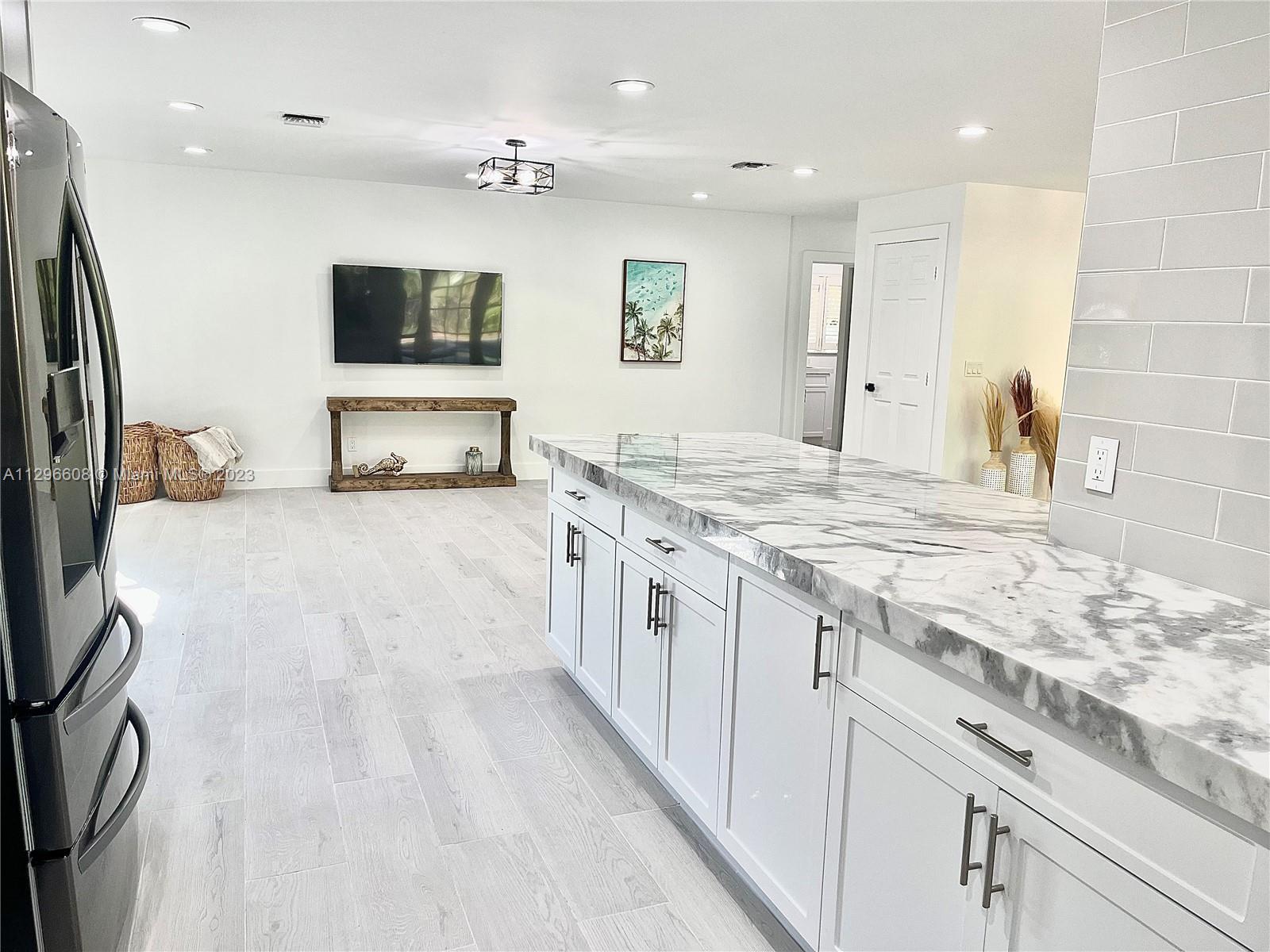 2875 Northwest 28th Street Boca Raton, FL 33434 - Photo 7 of 32 a large white kitchen with stainless steel appliances kitchen island granite countertop a large counter top and a stove top oven