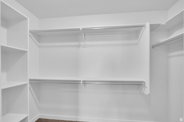 6120 North Sheps Ridge Road Eagle Mountain, UT 84005 - Photo 12 of 43 Walk-in closet featuring white built-in shelving, multiple hanging rods, and neutral-toned carpeting