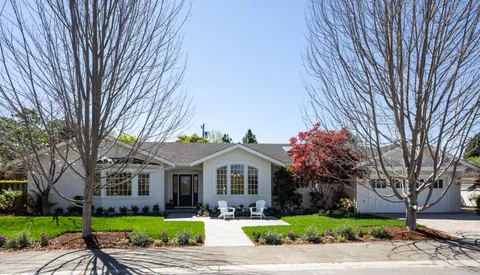 a front view of a house with a garden and trees