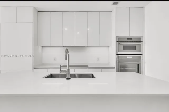 a kitchen with granite countertop white cabinets and stainless steel appliances