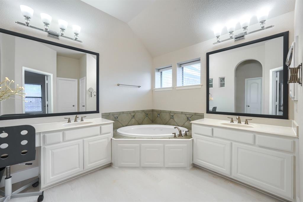 2246 Longview Road Irving, TX 75063 - Photo 31 of 40 Dual vanity with white cabinetry and integrated sinks, complemented by a built-in soaking tub featuring decorative tile surround