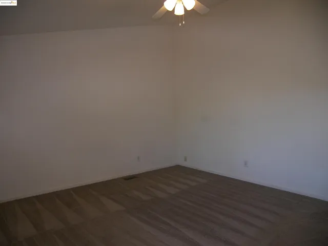 a view of a room with wooden floor and a ceiling fan