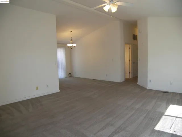 an empty room with a ceiling fan and window
