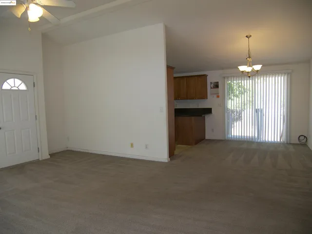 an empty room with chandelier fan and windows