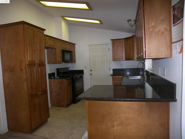 a kitchen with granite countertop a refrigerator and a sink