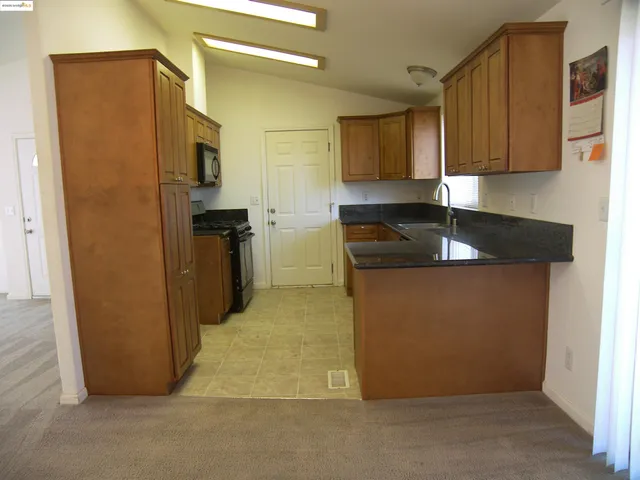 a kitchen with stainless steel appliances granite countertop a refrigerator a stove and a sink