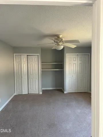 an empty room with chandelier fan and windows