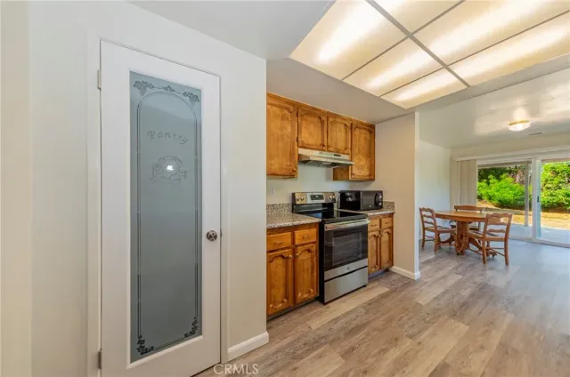 a kitchen with stainless steel appliances granite countertop a stove top oven a sink dishwasher a dining table and chairs with wooden floor