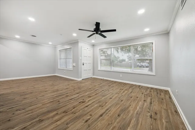 a view of empty room with wooden floor and fan
