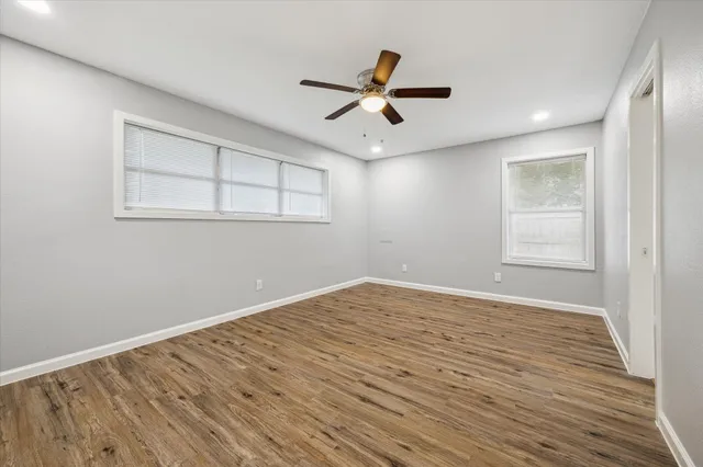 a view of empty room with wooden floor and fan