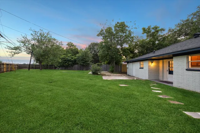 a backyard of a house with plants and large tree