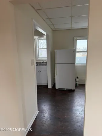 a view of a refrigerator in kitchen and an empty room