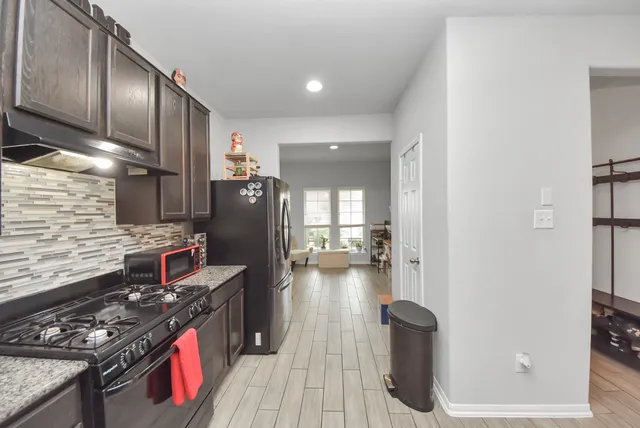 a kitchen with stainless steel appliances granite countertop a stove refrigerator and wooden floor