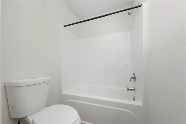a white toilet and shower sitting next to a white sink
