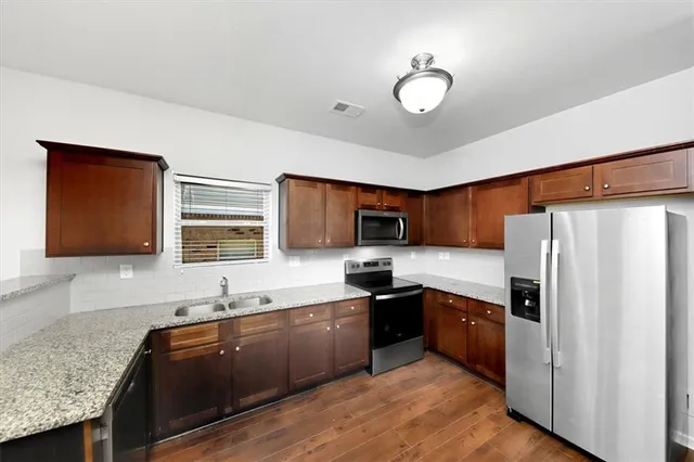 a kitchen with stainless steel appliances granite countertop a sink refrigerator and cabinets