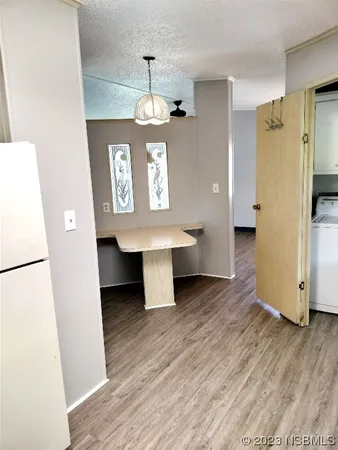a view of a hallway with wooden floor stairs and a refrigerator