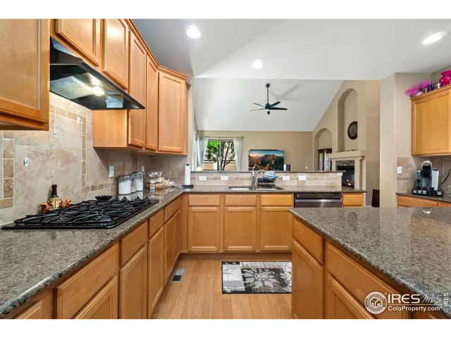 a kitchen with stainless steel appliances granite countertop a sink a stove and a wooden cabinets