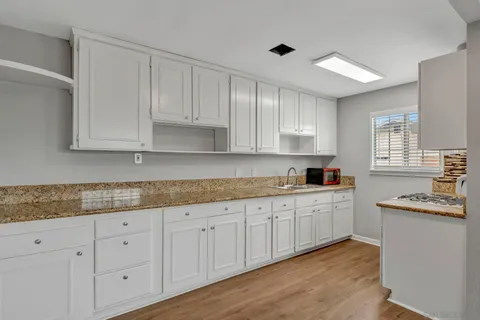 a kitchen with granite countertop white cabinets and white appliances