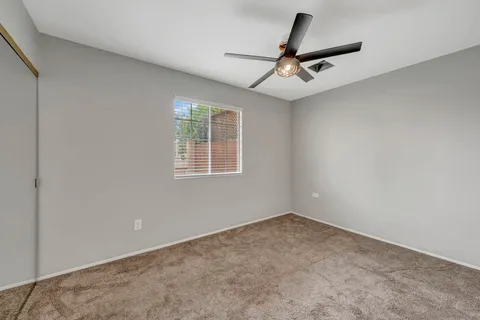 an empty room with a ceiling fan and window