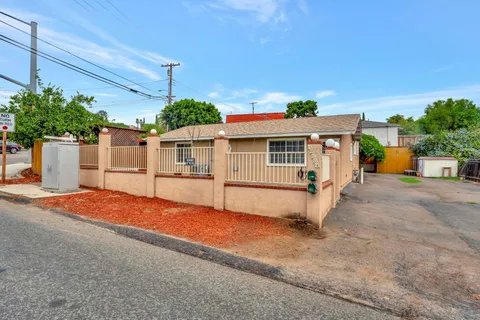 a view of a white house with a yard and fence
