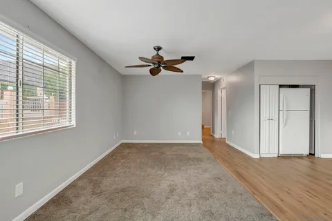 a view of an empty room with a ceiling fan and window
