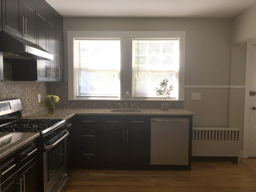 90 Orchard Street, Unit 1 Boston, MA 02130 - Photo 7 of 10 a kitchen with granite countertop a stove a sink and a window