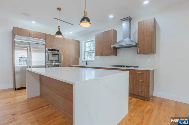 a kitchen with stainless steel appliances granite countertop a sink a stove and a wooden floors