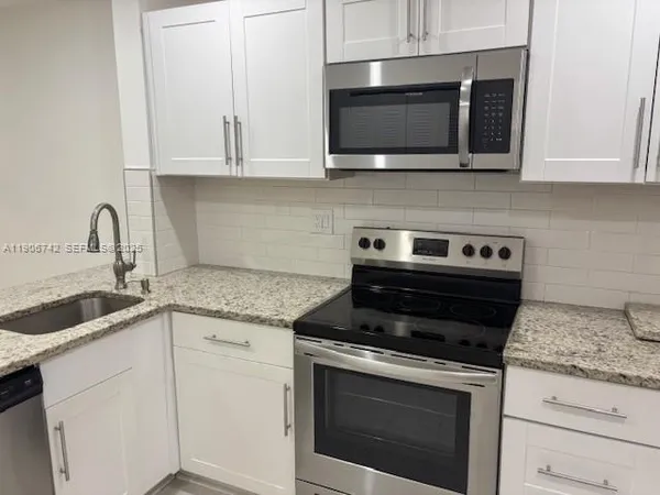 a kitchen with granite countertop white cabinets and black appliances