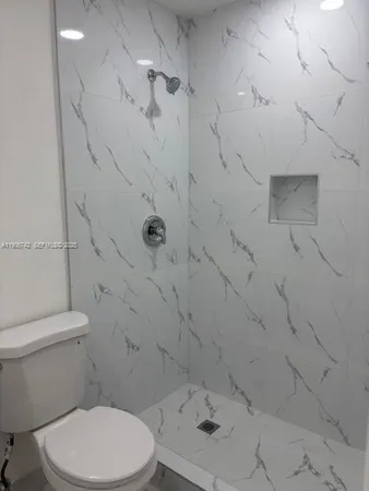 a white toilet sitting next to a shower