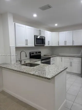 a kitchen with stainless steel appliances granite countertop a sink a stove a microwave a sink and cabinets