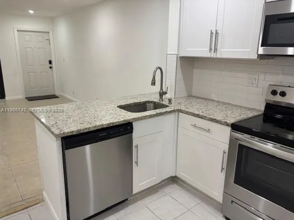 a kitchen with granite countertop a sink stove and cabinets