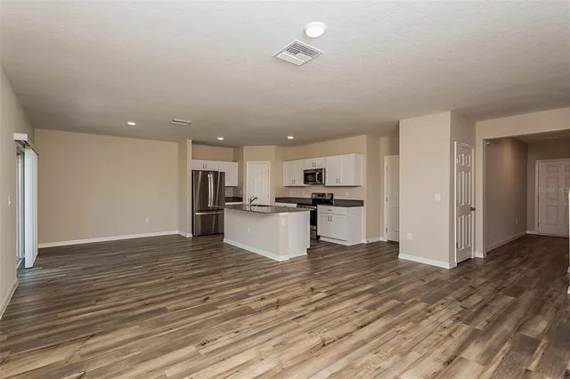 a view of kitchen with kitchen island wooden floor and refrigerator