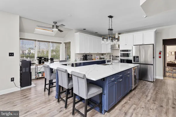 a kitchen with stainless steel appliances a center island wooden floor and a window