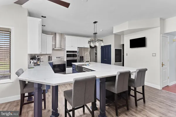 a kitchen with stainless steel appliances kitchen island granite countertop a dining table chairs and a refrigerator