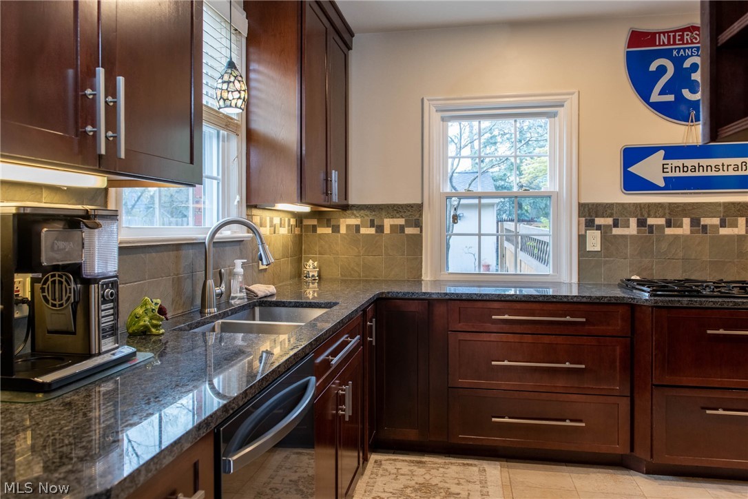 3433 Bradford Road Cleveland, OH 44118 - Photo 6 of 35 From the side dr, is this gorgeous designer Kitchen, providing an abundance of Granite counters & Dbl SS sinks (2020). Tall quality cabinets w/ crown molding & drawers offer handsome hardware. All Kit Appl's are Incl. A Newer pendant light fixture & under counter lighting accent the tiled back splash. In the lower corner ahead, is a Lazy Susan garbage space for your throw away's & recyclables.