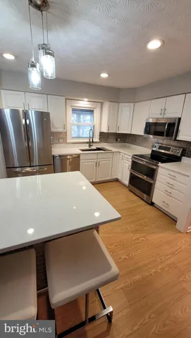 a kitchen with stainless steel appliances kitchen island granite countertop a sink and white cabinets