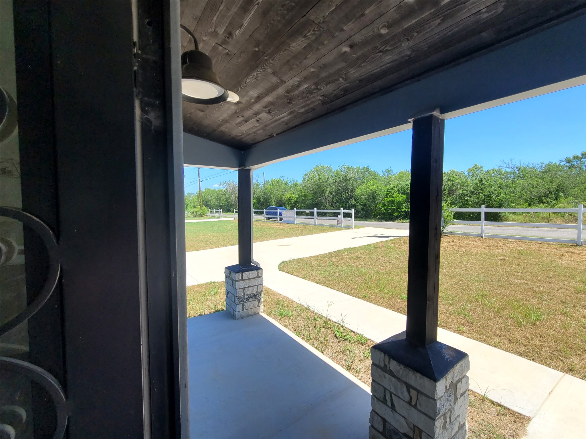 422 A Road Stockdale, TX 78160 - Photo 5 of 40 A welcoming covered porch with stone-accented pillars overlooks a fenced yard and driveway.