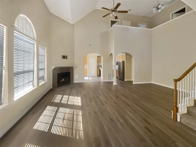 a view of an empty room with wooden floor fireplace and a window