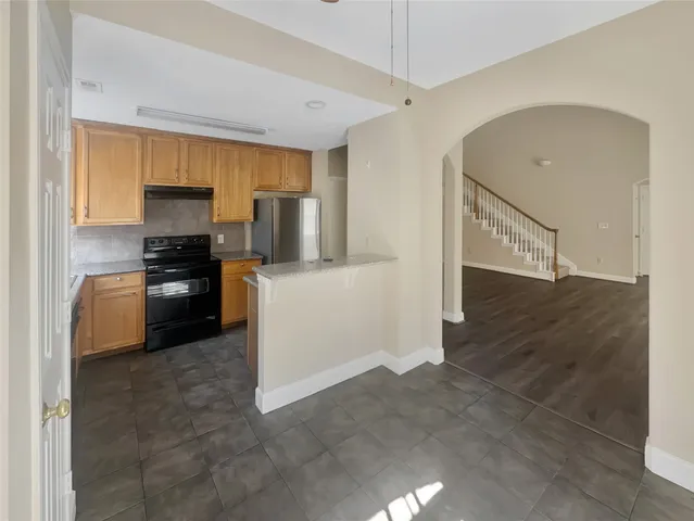 a kitchen with granite countertop a refrigerator and a stove top oven
