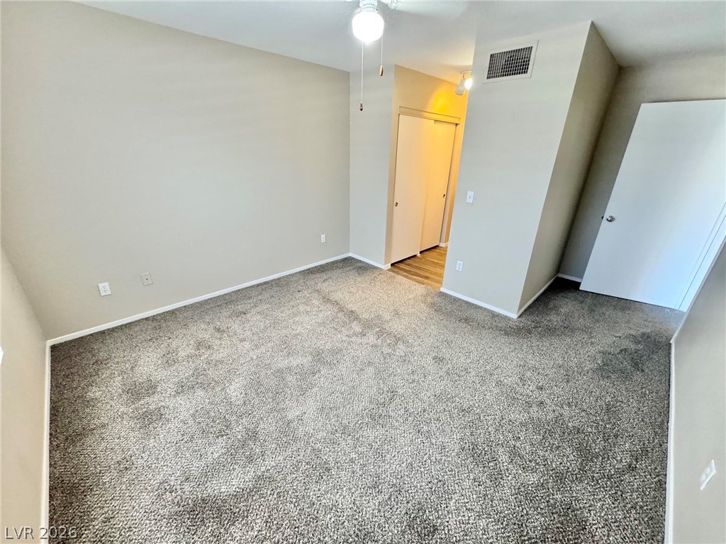 8070 West Russell Road, Unit 2121 Las Vegas, NV 89113 - Photo 13 of 22 A spacious, naturally illuminated room featuring plush carpeting and modern doors, offering a clean and inviting atmosphere.