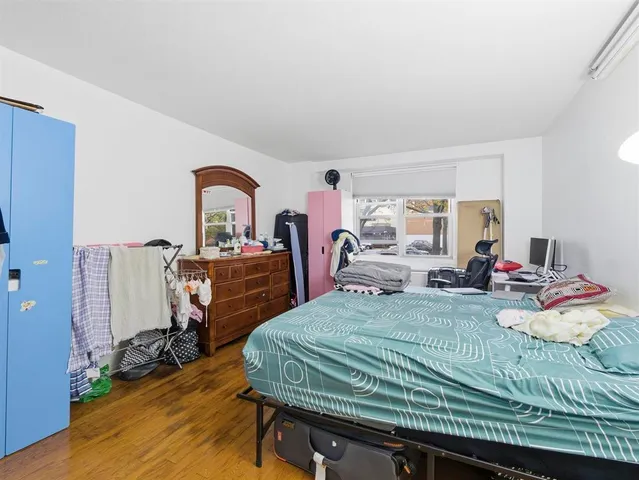 a bed sitting in a bedroom next to a window with bookshelf and wooden floor